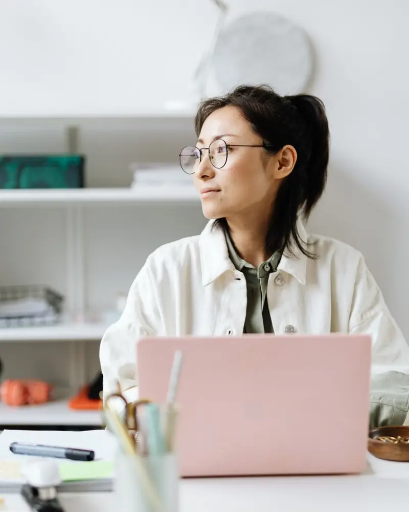 Mulher de óculos na mesa do escritório, com o notebook (foto ilustrativa)
